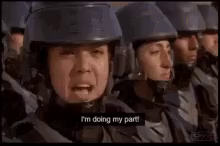 a row of soldiers wearing helmets are standing in a line each time someone says something they are saying "I'm doing my part" with a little kid at the end and everyone laughs. From the satirical movie Starship Troopers